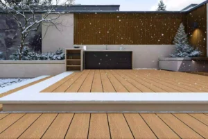 Light wood-grain WPC decking in a snowy courtyard, creating a clean, expansive backdrop for minimalist wood and stone architecture with frost-touched greenery.