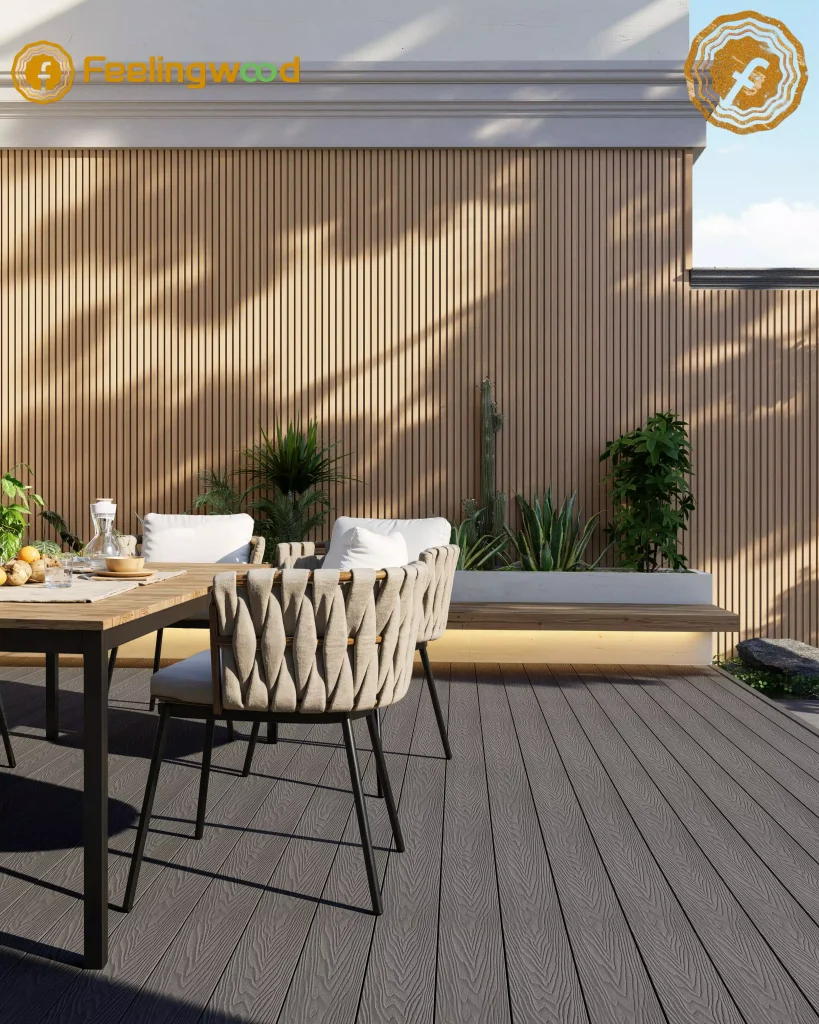 Feelingwood WPC decking and cladding in a stylish outdoor dining space, with dark grey decking and vertical-groove wall paneling.