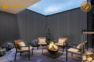 Modern outdoor patio featuring dark gray Feelingwood fluted wall panels, surrounded by snow-covered landscaping, a central fire pit, and wooden lounge chairs, creating a cozy winter outdoor living space.